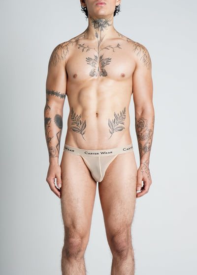 Man wearing beige Carter Wear underwear on a gray background