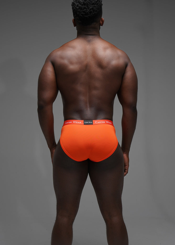 Man wearing bright orange underwear with a gray background